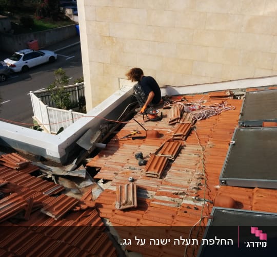 אדם עובד על גג רעפים עם כלי עבודה וחבלים